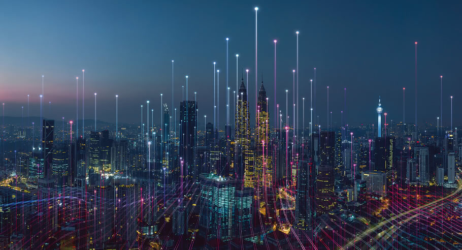 A colorfully lit nighttime city with beams of light shooting into the sky